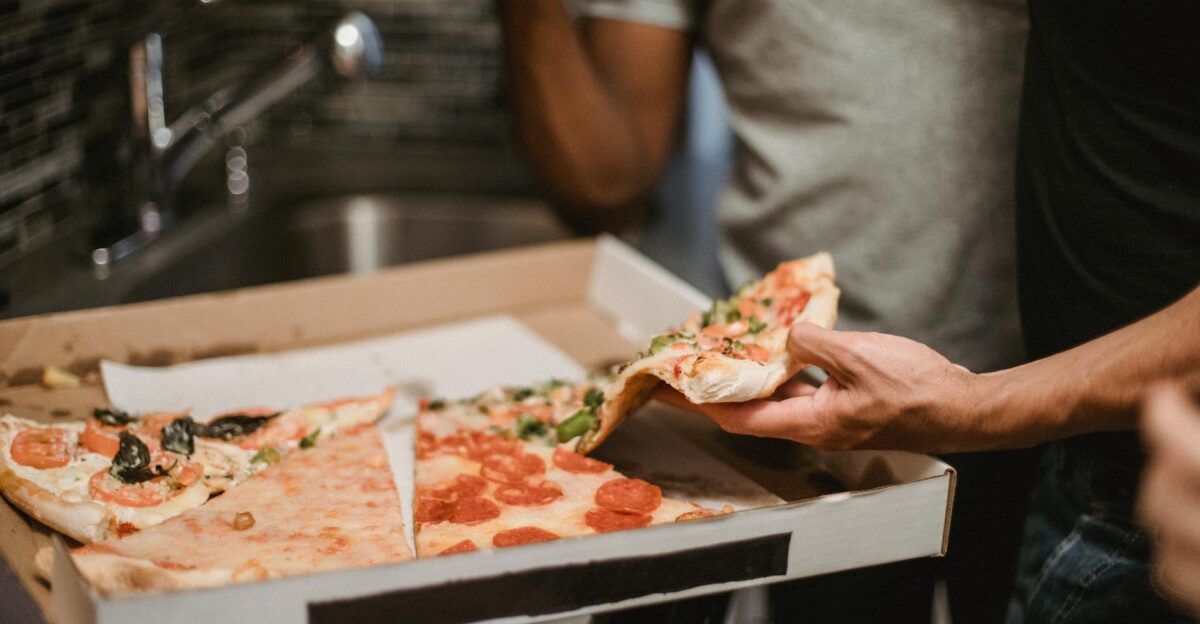 Close-up of friends sharing a pizza showing diverse toppings and human interaction