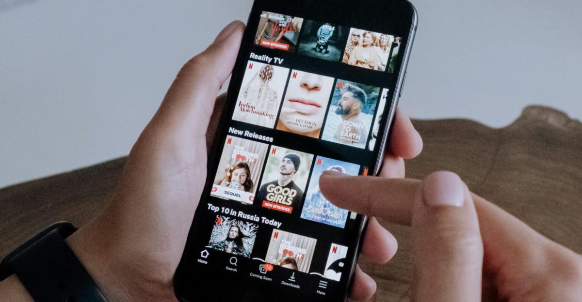 A person using a smartphone to explore and select shows on a streaming platform indoors.