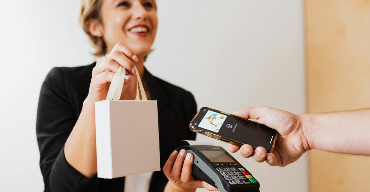 Smiling cashier handles a purchase with a contactless mobile payment in a modern shop
