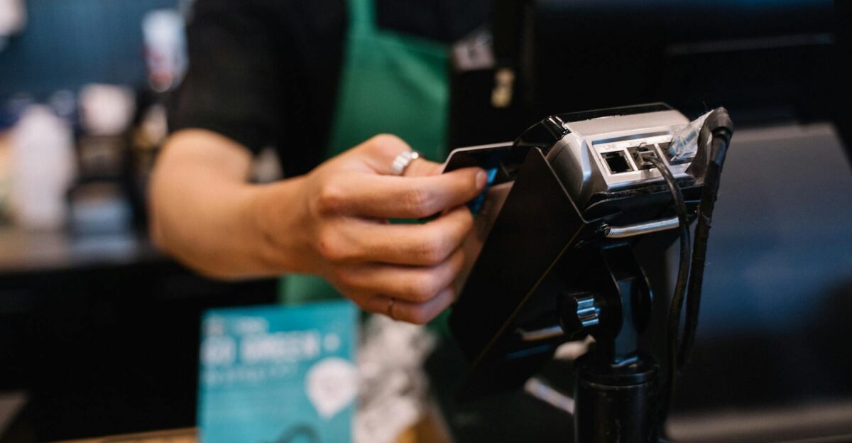 Close-up of a barista processing a payment using a card reader in a caf setting