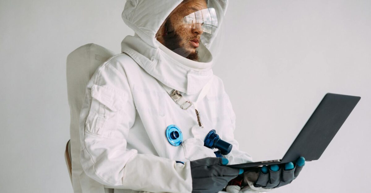 An astronaut in a space suit working on a laptop indoors blending technology and exploration