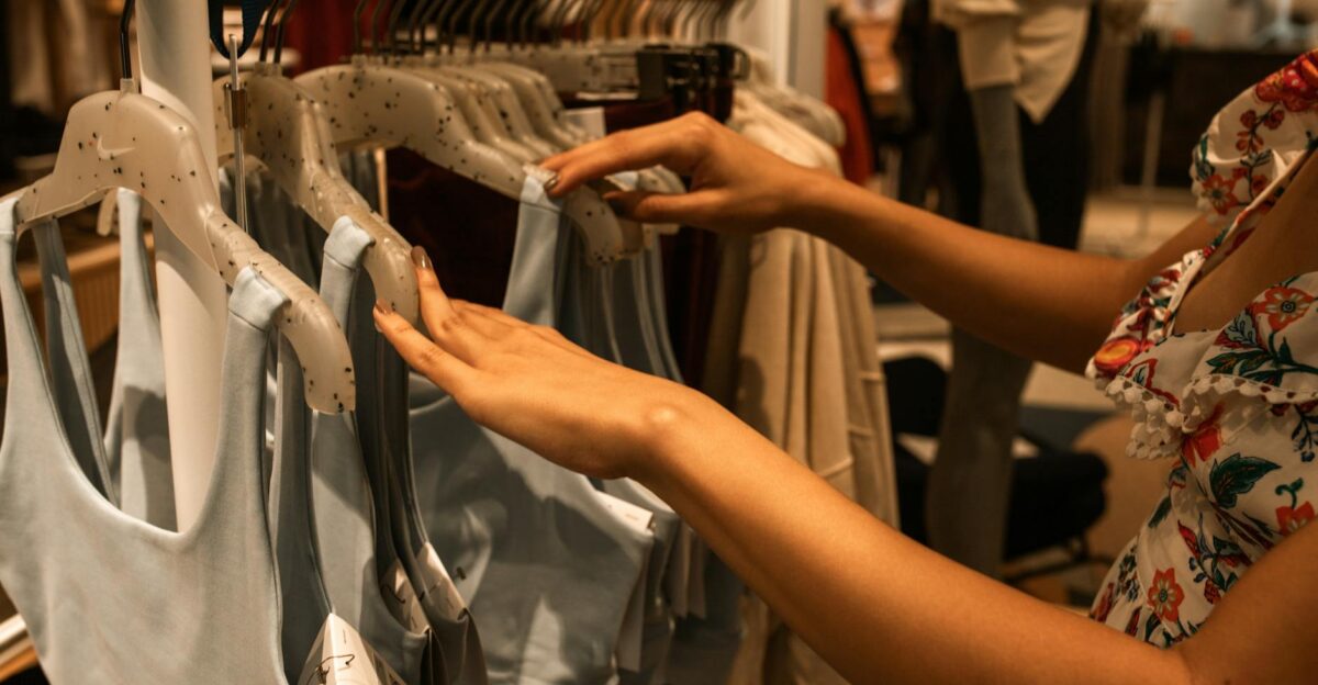 A woman selecting blue tops from a clothing rack inside a fashion boutique