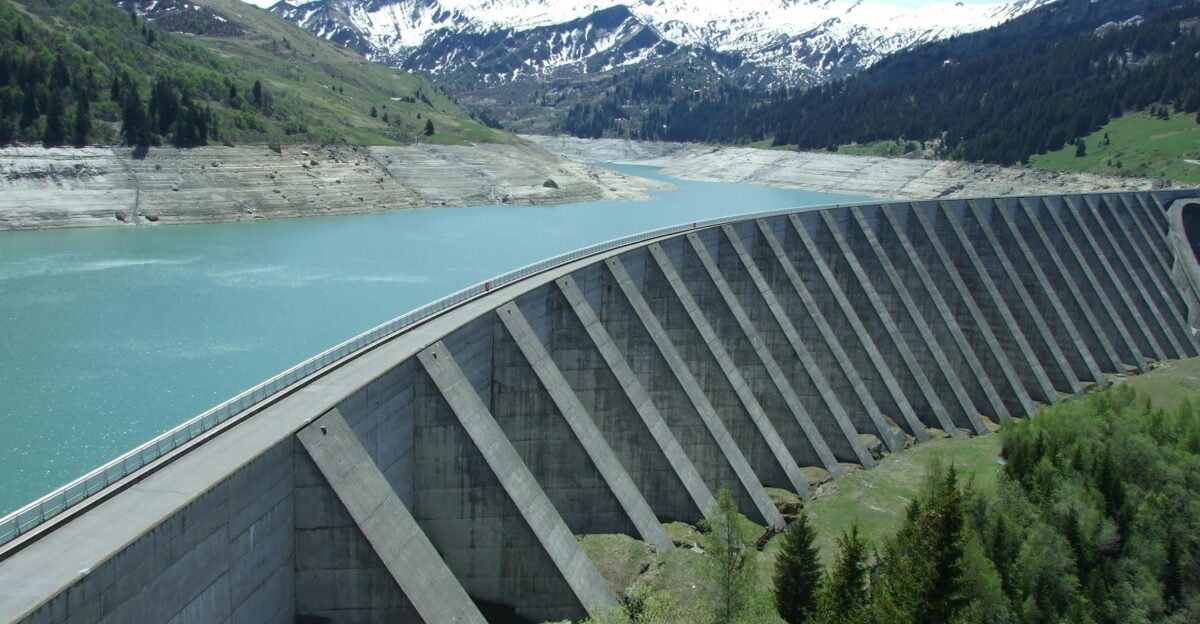 A breathtaking view of a dam amidst a serene alpine landscape with snow-capped mountains