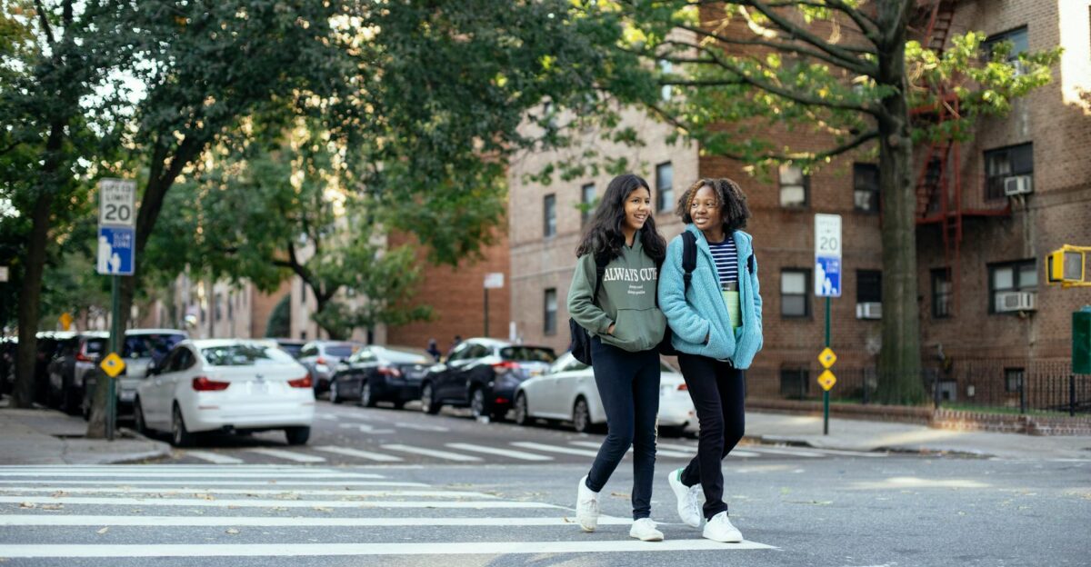 Two friends crossing a city street on a sunny autumn day enjoying a casual stroll