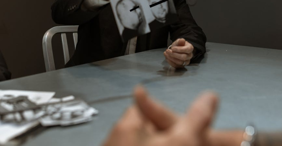 A police officer questioning a handcuffed suspect in an interrogation room