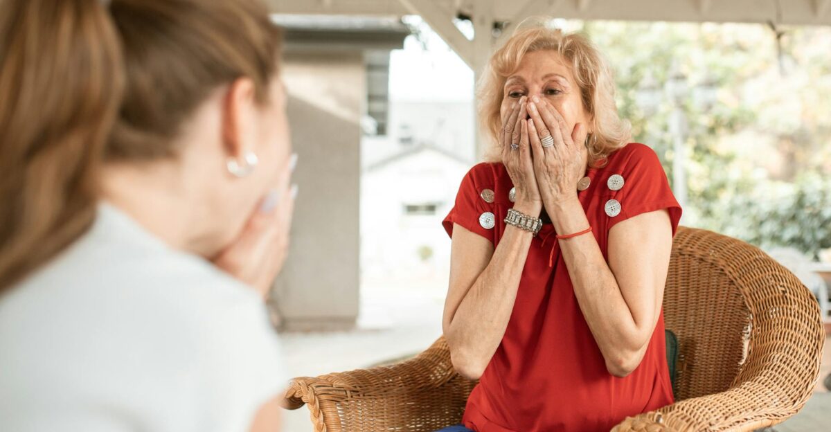 An elderly woman expresses surprise and joy during an outdoor conversation