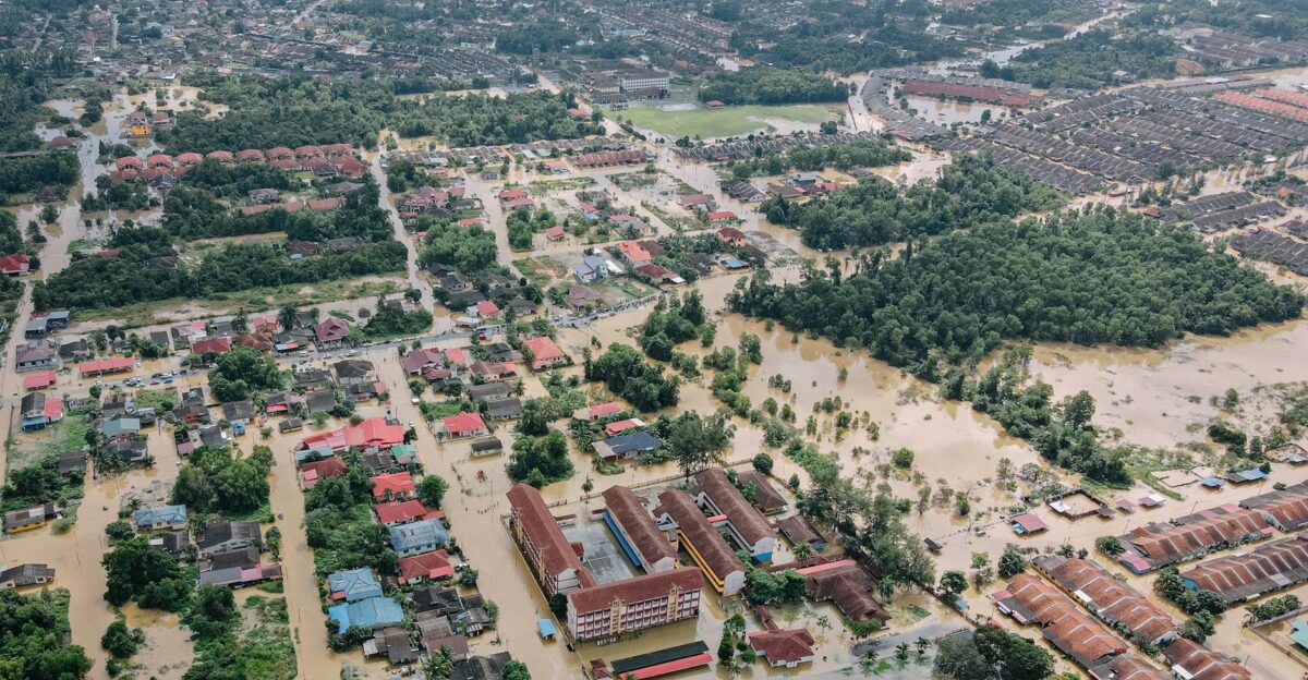 Aerial view of flooded small town with many residential houses and lush green trees