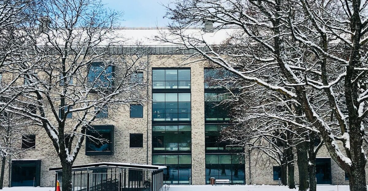 A snow-covered building surrounded by bare trees during winter