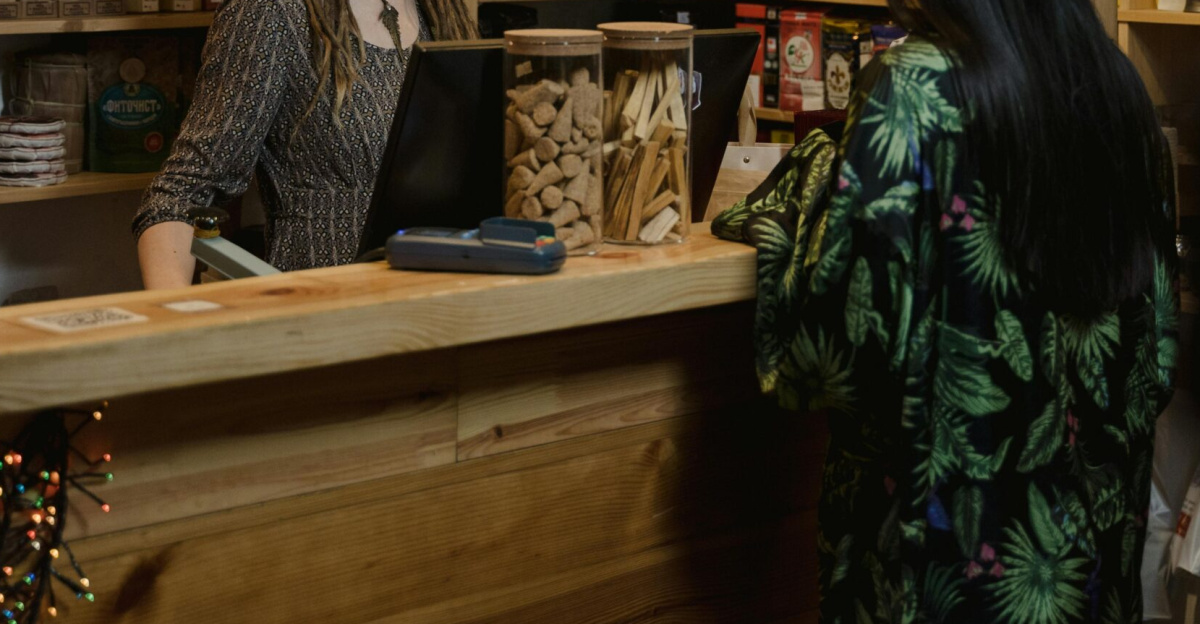 Woman customer interacting at a wood-accented store checkout, surrounded by various merchandise.