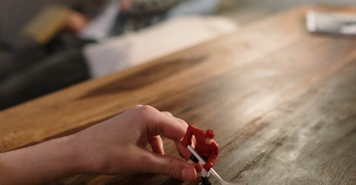 A child playing with a toy hockey player on a wooden table with a blurred background