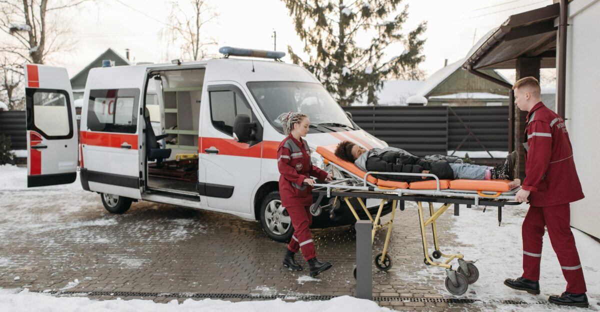 Paramedics transporting a patient on a stretcher to an ambulance on a snowy day
