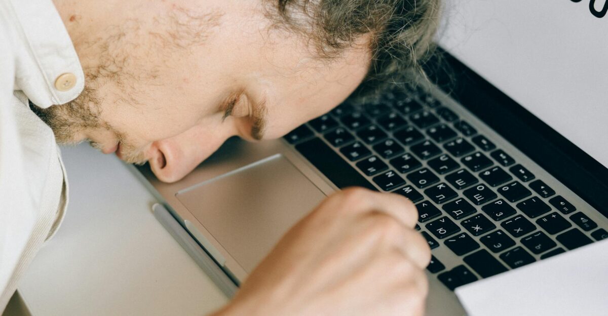 Exhausted employee resting head on laptop keyboard due to burnout and stress
