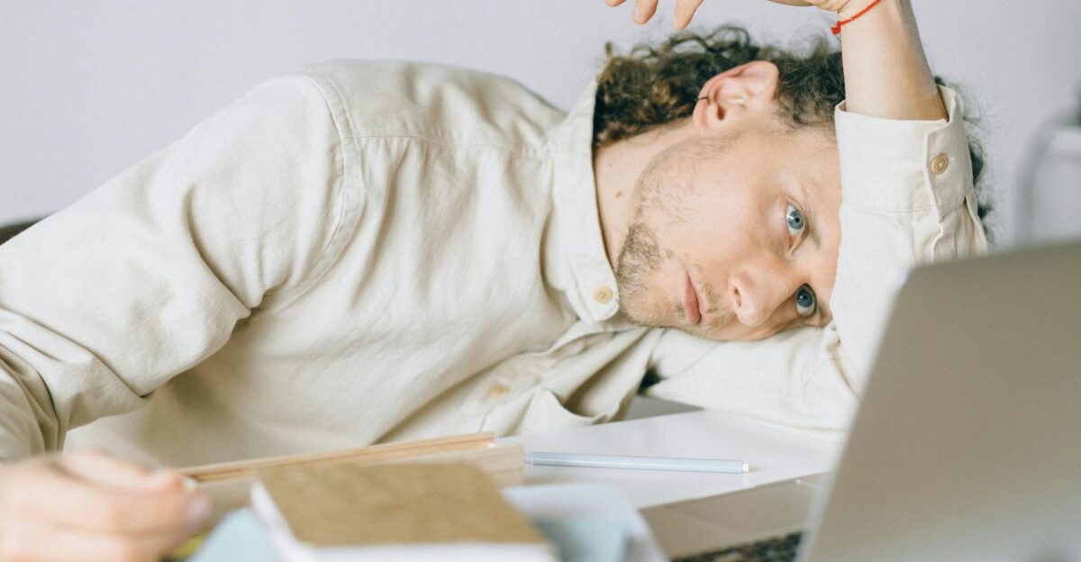 A tired Caucasian man at a desk showing signs of exhaustion and stress exemplifying workplace burnout