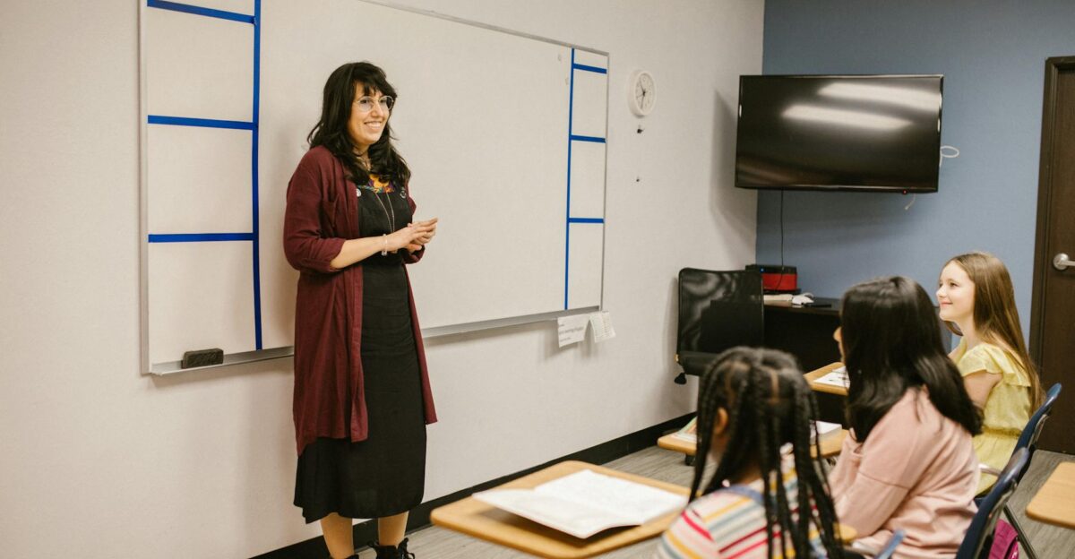 A teacher conducts a lesson with attentive diverse students in a modern classroom setting