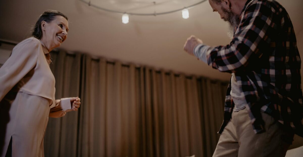 A lively senior couple dancing indoors with smiles enjoying a joyful moment together