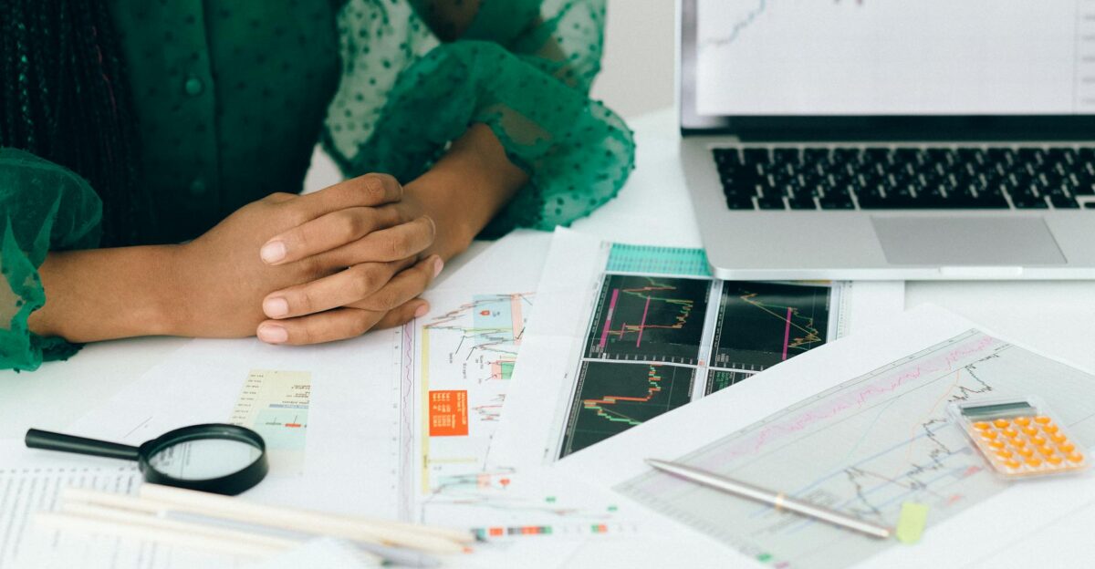 A person analyzes financial charts and graphs at a desk indicating business trading activity