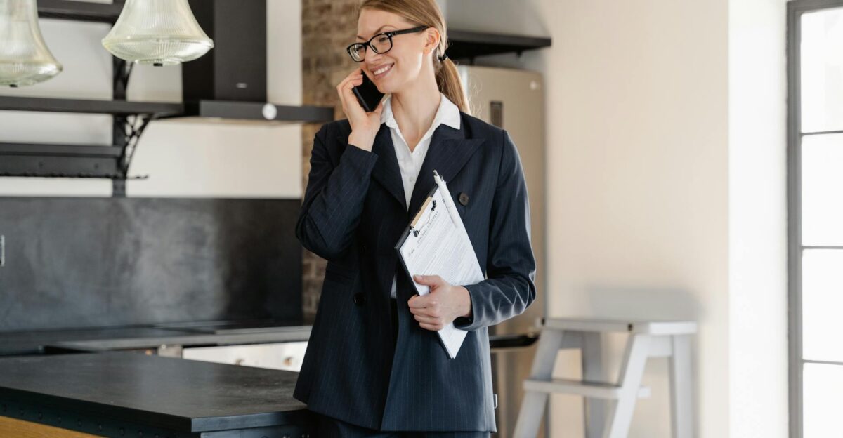 Confident businesswoman in office attire making a call while holding a clipboard in a modern workspace