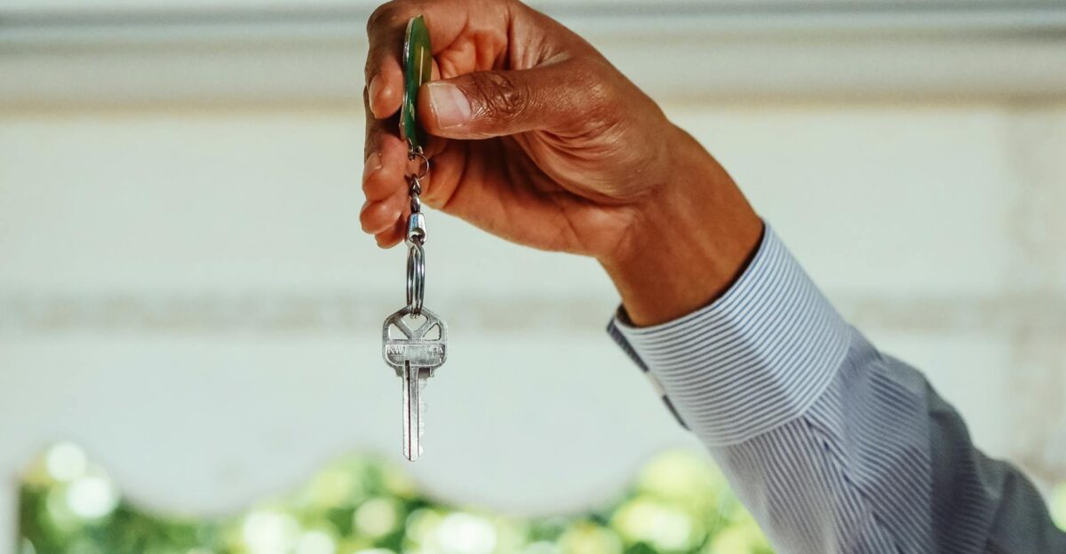 A hand holding a set of house keys symbolizing buying or renting a new home