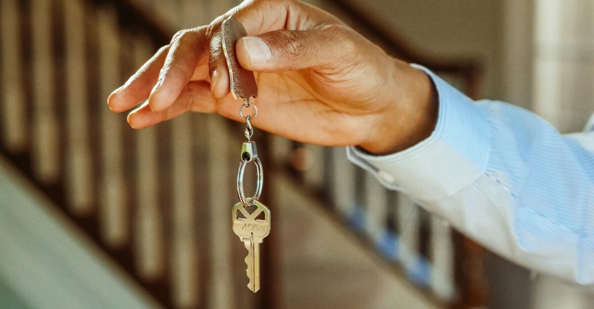 A close-up shot of a hand holding a house key indicating new ownership or rental