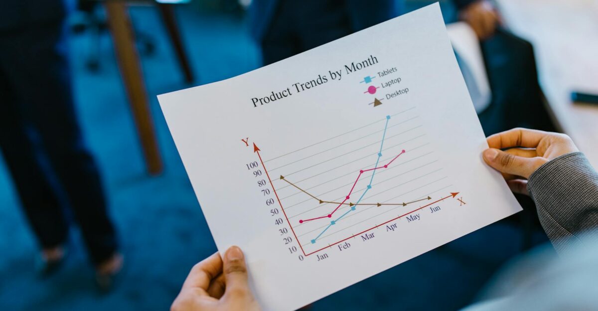 Close-up of hands holding a product trend chart in a corporate office setting
