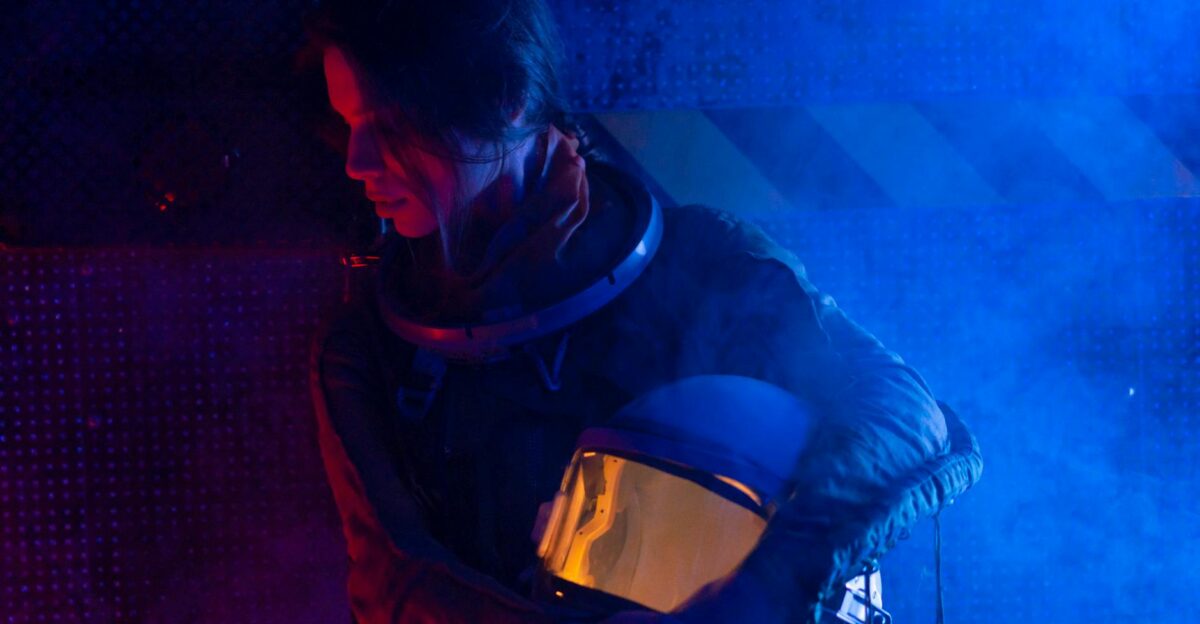 A futuristic portrait of a female astronaut holding her helmet in a dramatic blue light setting