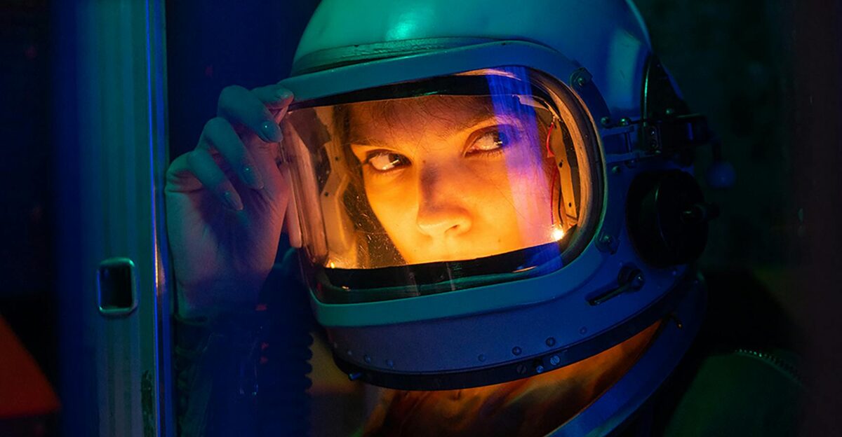 Portrait of a spacewoman in a helmet gazing intensely with colorful lighting