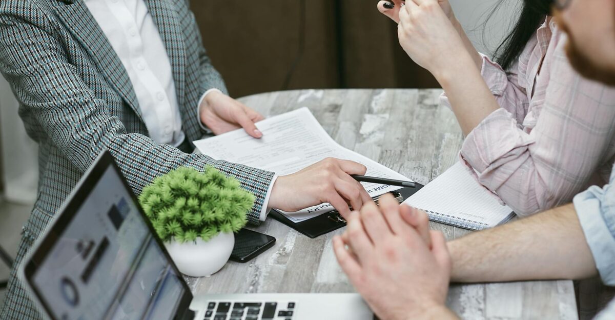 Professional meeting discussing business agreements with laptops and documents on a rustic table