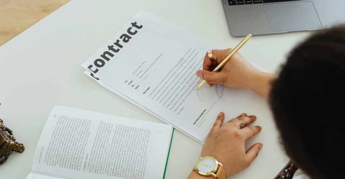 Professional signing a business contract at a modern desk setup for office work