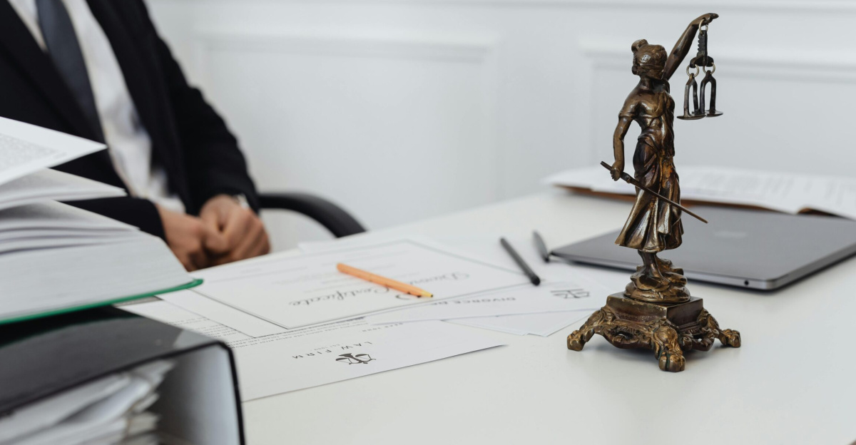 A legal professional's workspace featuring Lady Justice statue, documents, and a laptop.