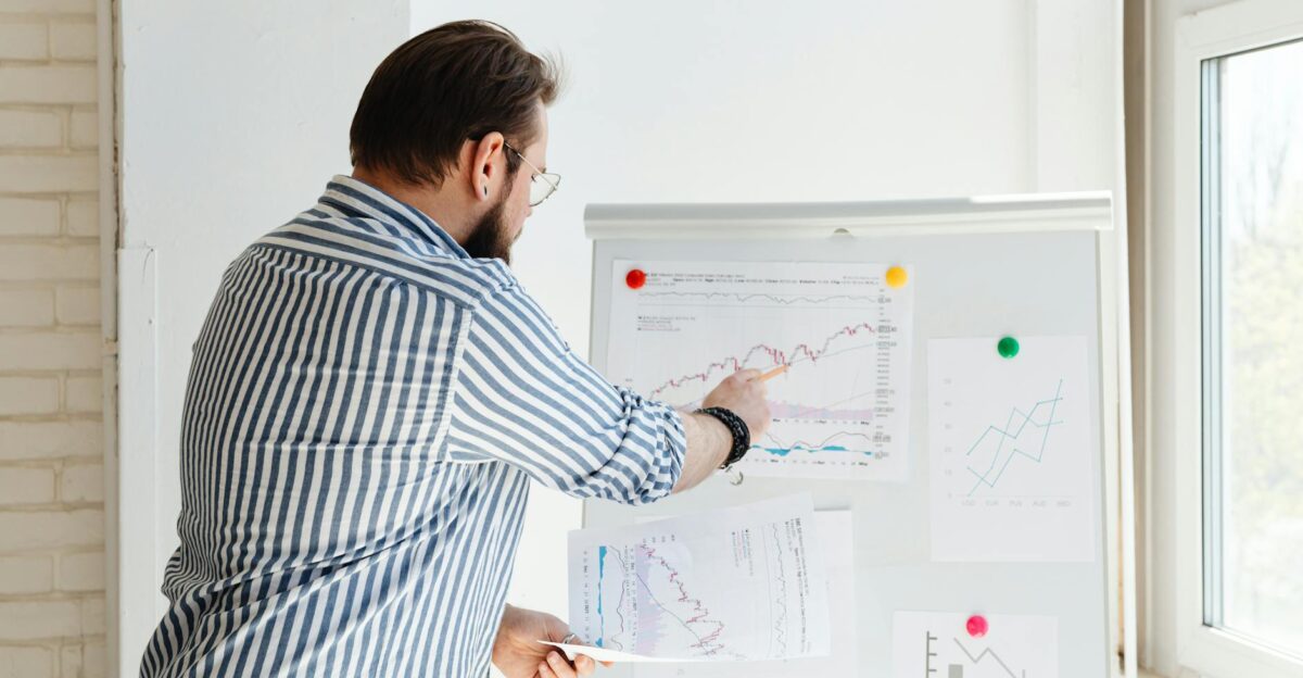 A businessman pointing at financial charts on a whiteboard discussing stock market trends