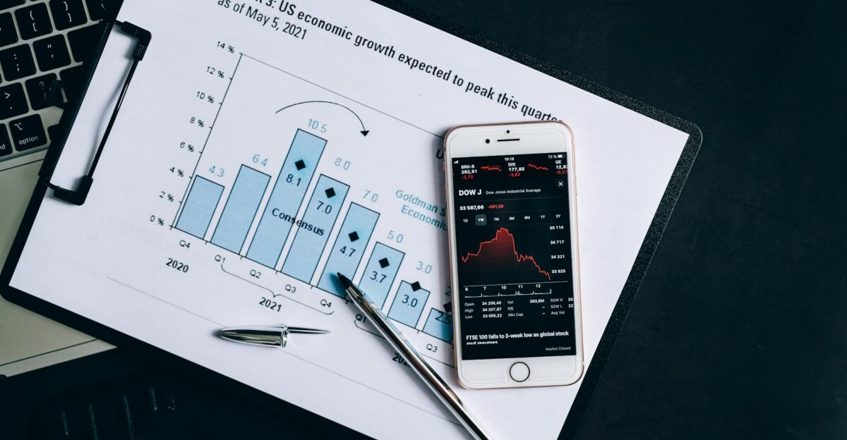 A smartphone displaying stock data rests on a financial report graph