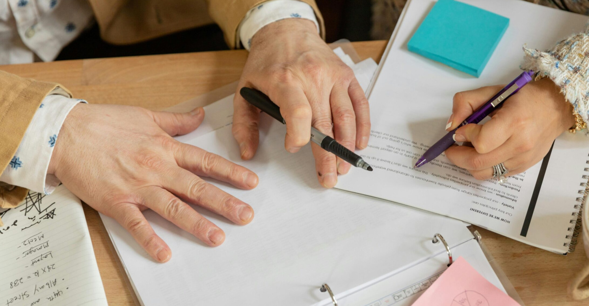 Close-up of two coworkers collaborating over documents and planning in an office setting.