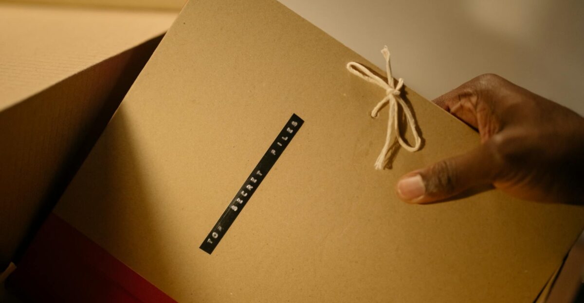 Close-up of hand holding top secret document folder in a box