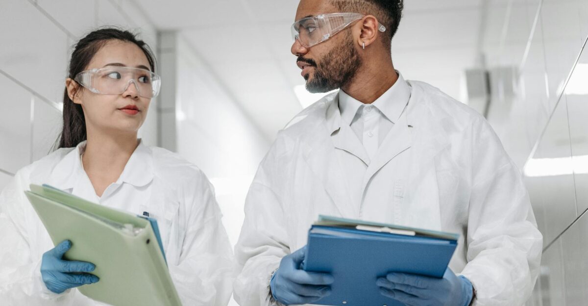 Two scientists in protective gear discuss research in a laboratory setting focused on collaboration and safety