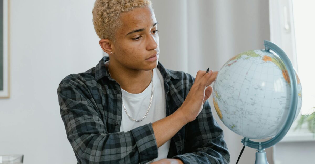 A young man indoors examining a globe symbolizing education and exploration
