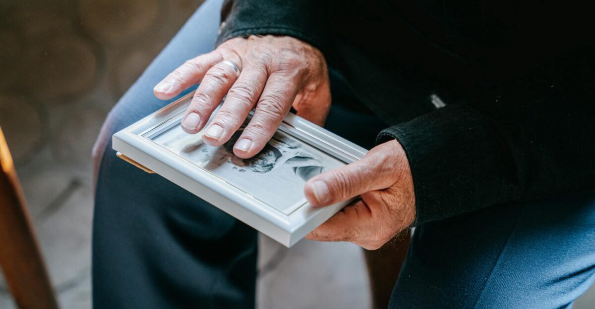 Close-up of elderly hands holding a framed photograph reflecting nostalgia and emotion