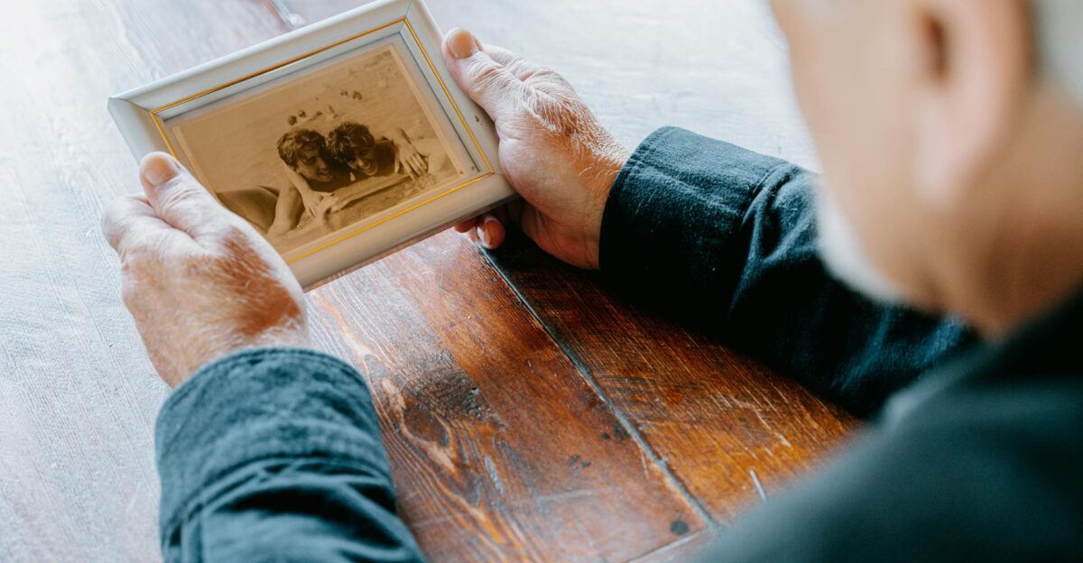 A senior man in black long sleeves holding an old photograph evoking nostalgia and reflection