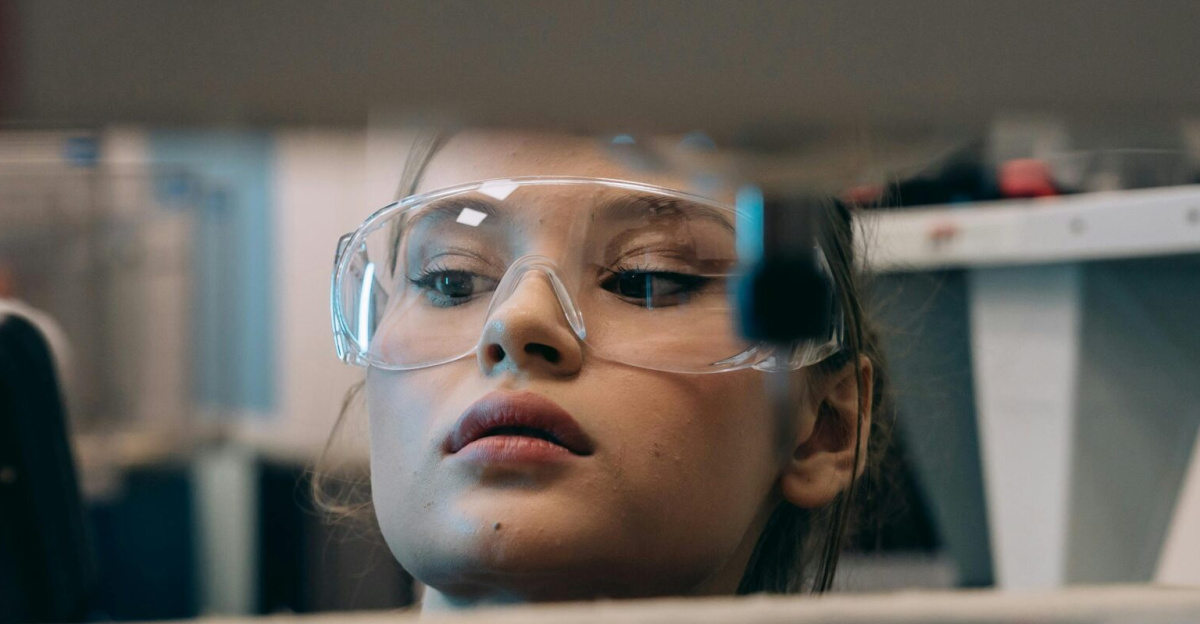 Woman wearing protective goggles working intently in an industrial workshop.