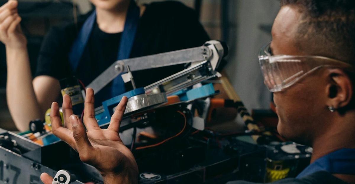 Three engineers collaborate in an indoor workshop on robotics assembly and programming.