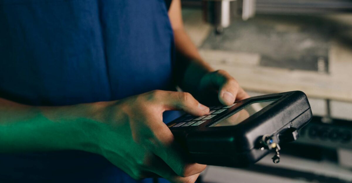 Close-up of technician using a handheld control device in a manufacturing setting