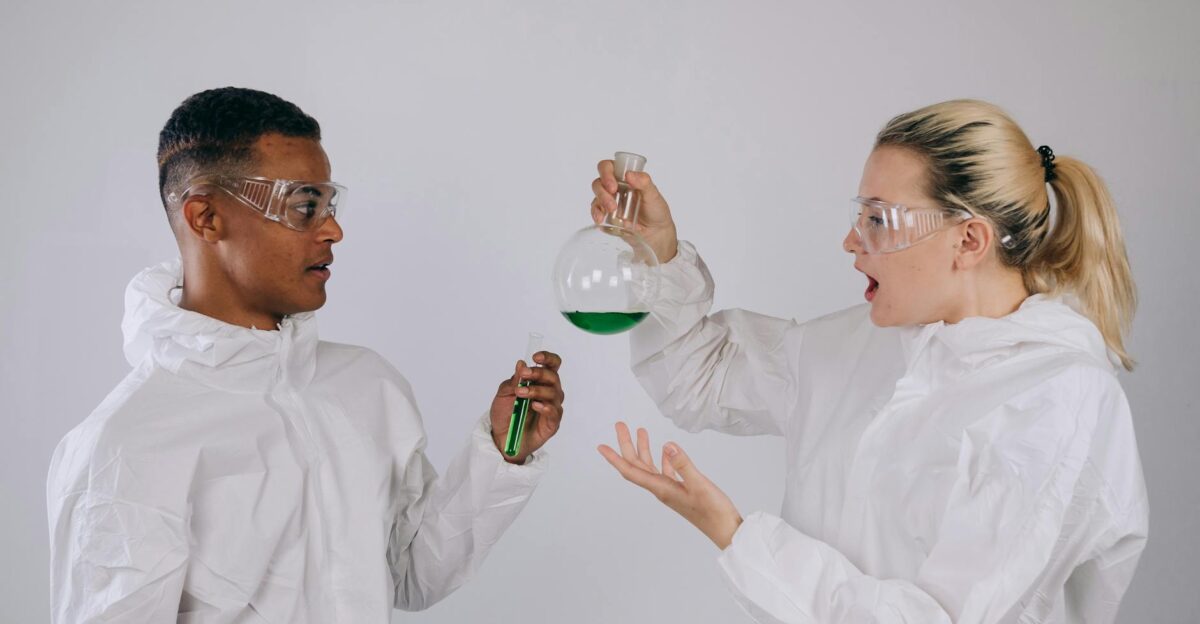 Two scientists in protective gear conducting an experiment with green liquid in laboratory setting