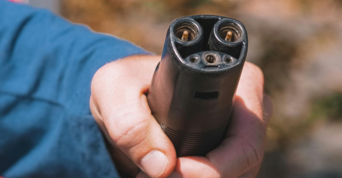Close-up shot of a hand holding an electric vehicle charger, symbolizing clean energy.