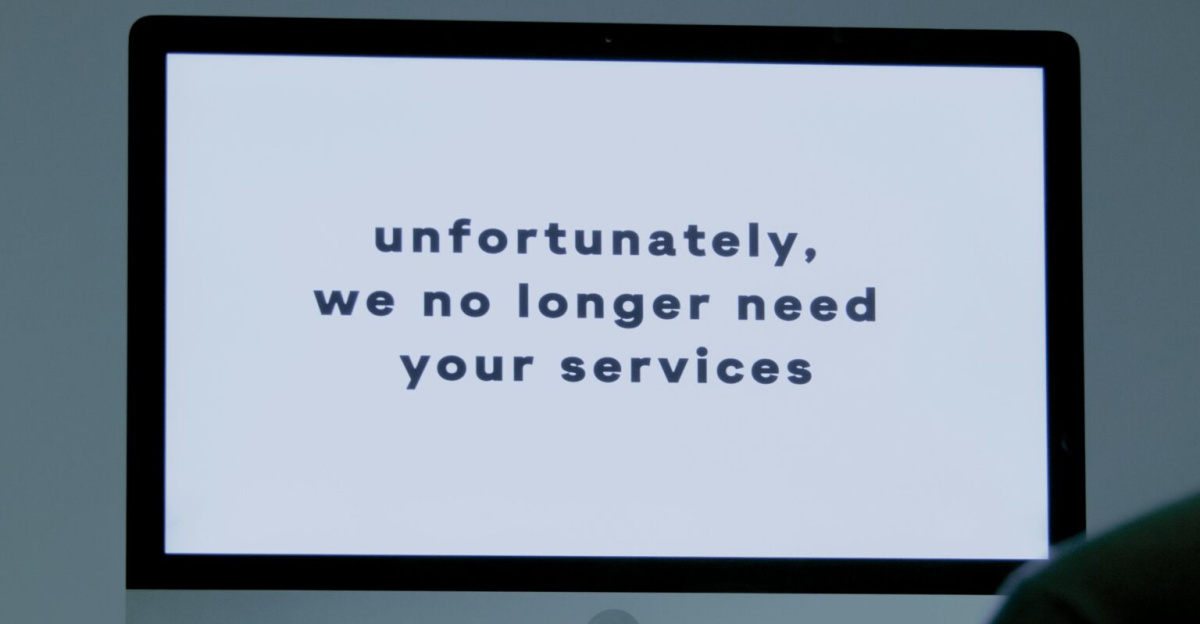 A computer screen displays a termination message, indicating job loss or unemployment.