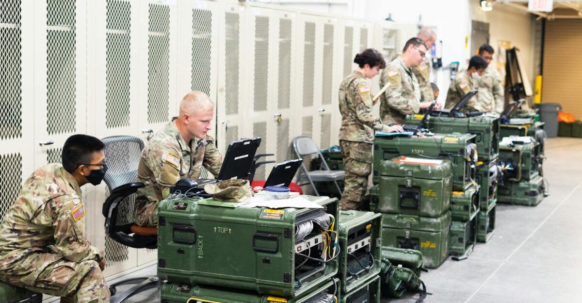 A group of military personnel in uniforms using computers and communication equipment in a secure indoor facility