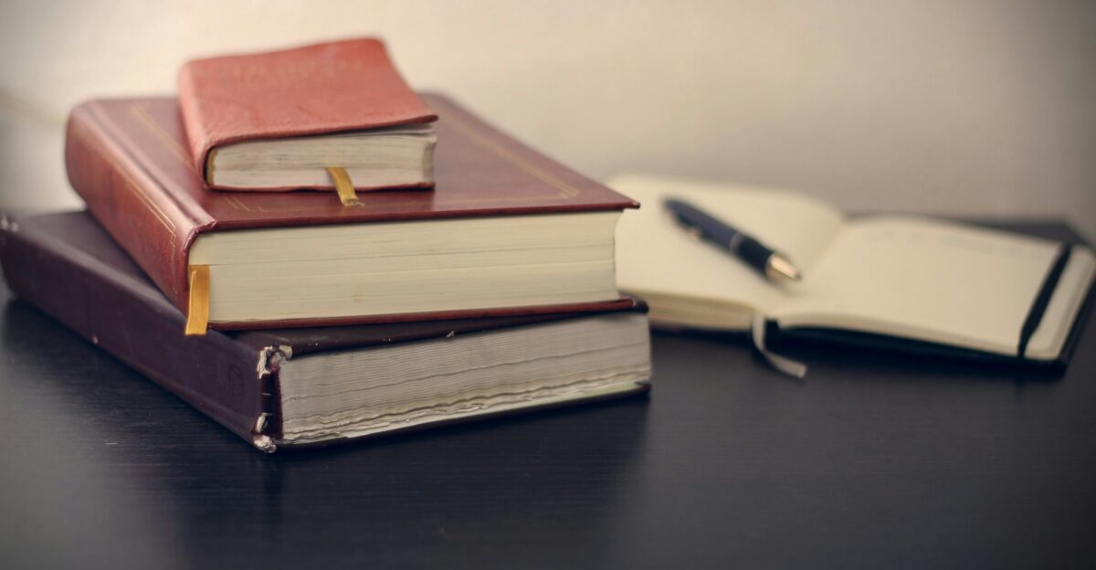 selective focus photography of three books beside opened notebook