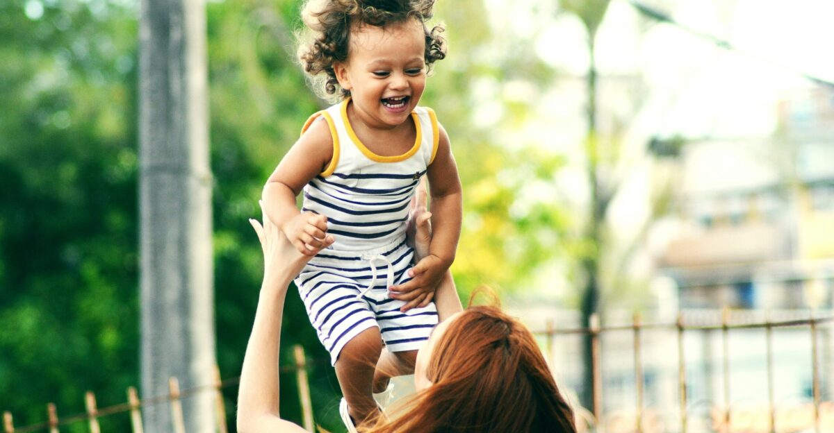selective focus photo of woman lifting child during daytime