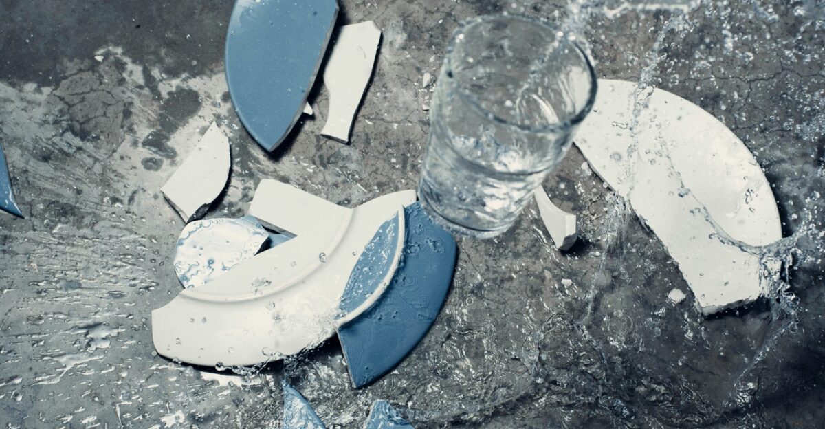 broken white and blue ceramic plate and clear beverage glass with water
