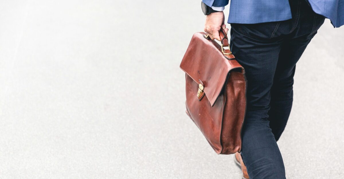 person walking holding brown leather bag
