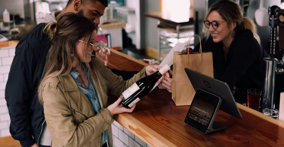 woman holding wine bottle beside man in front of woman smiling