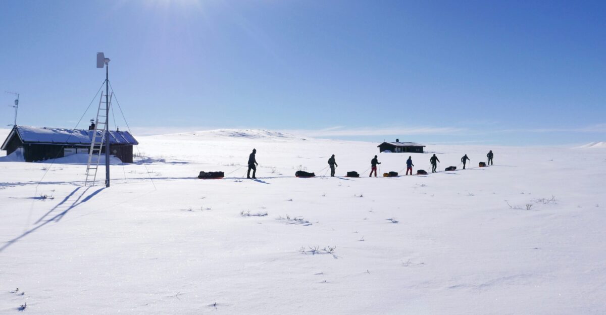 people standing on snowy field near house during daytime